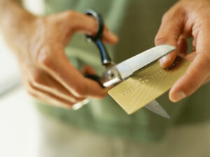 close-up of human hands cutting a credit card by scissors